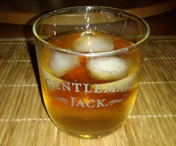 An adult beverage made of Black Velvet Canadian whiskey, their Toasted Caramel flavor infused variety, with ice and water too, in a classy Gentleman Jack glass by the Jack Daniels folks down in Tennessee.