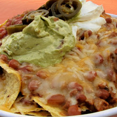 Beautiful photo of a supreme nacho dish with guacamole and refried beans, the pinicle of Tex-Mex cuisine.