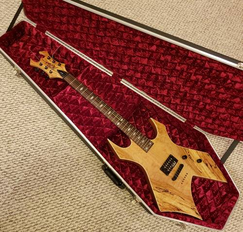 Resting in it's genuine Coffin Case is an awesome B.C Rich Warlock Exotic Model electric guitar with wood of natural spalted maple.