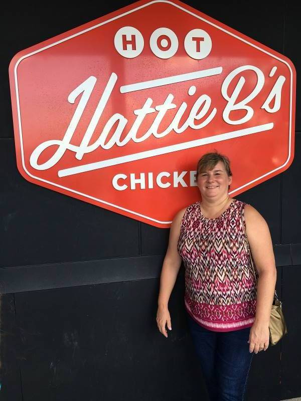 Ms. Paula Hahnert of Louisville, Kentucky standing before a sign at the entrance of Hattie B's Hot Chicken, which some consider to be the best hot chicken in Nashville, Tennessee.
