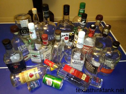 A collection of empty bourbon whiskey bottles and shot glasses laid out on a ping pong table in Louisville, Kentucky.