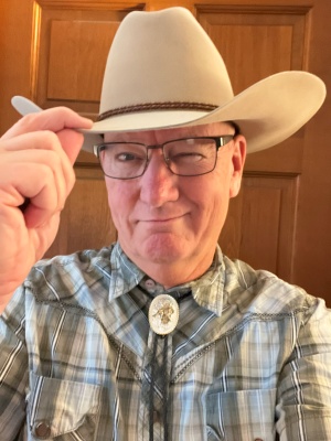 Chrome Dome Mike Kimbro in a western shirt, cowboy hat, and a bolo tie.n January 2019.