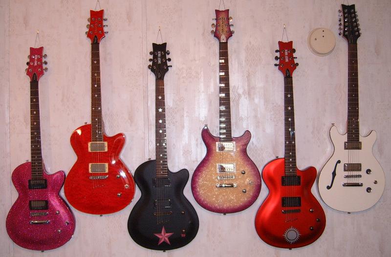 My Daisy Rock Electric Guitar Collection, including (from L to R) the Rock Candy in Atomic Pink, the Rock Candy Special, the Dark Star model of the Rock Candy Custom, the Stardust Elite, the Aztec Goddess model of the Rock Candy Custom, and the Retro-H 12-String guitar.  