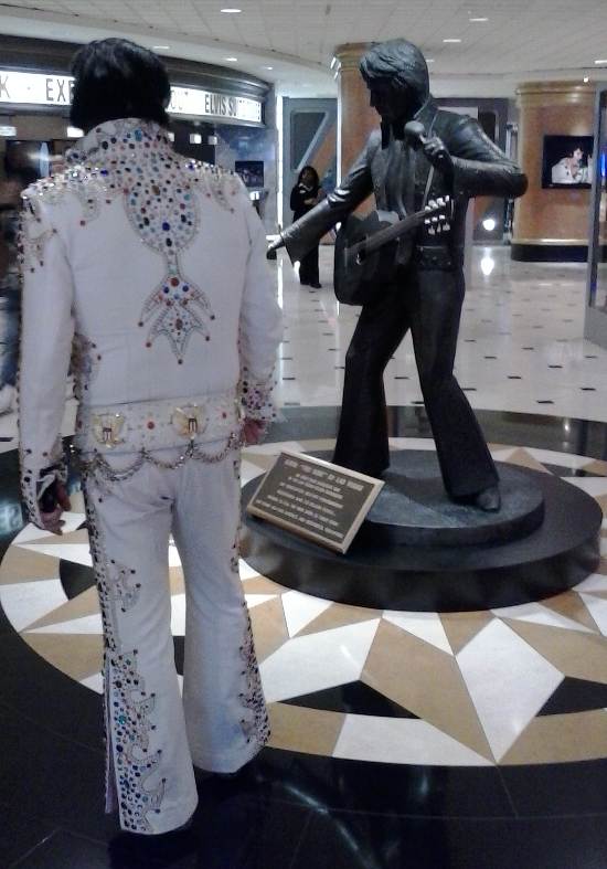 Photo of an Elvis impersonator in front of the statue of Elvis Presley in the lobby of the Westgate Resort and Casino in Las Vegas, Nevada.